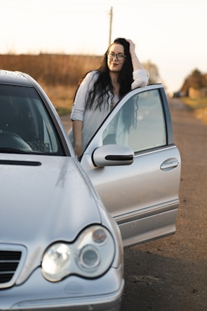 Woman poses by her car with an open door.