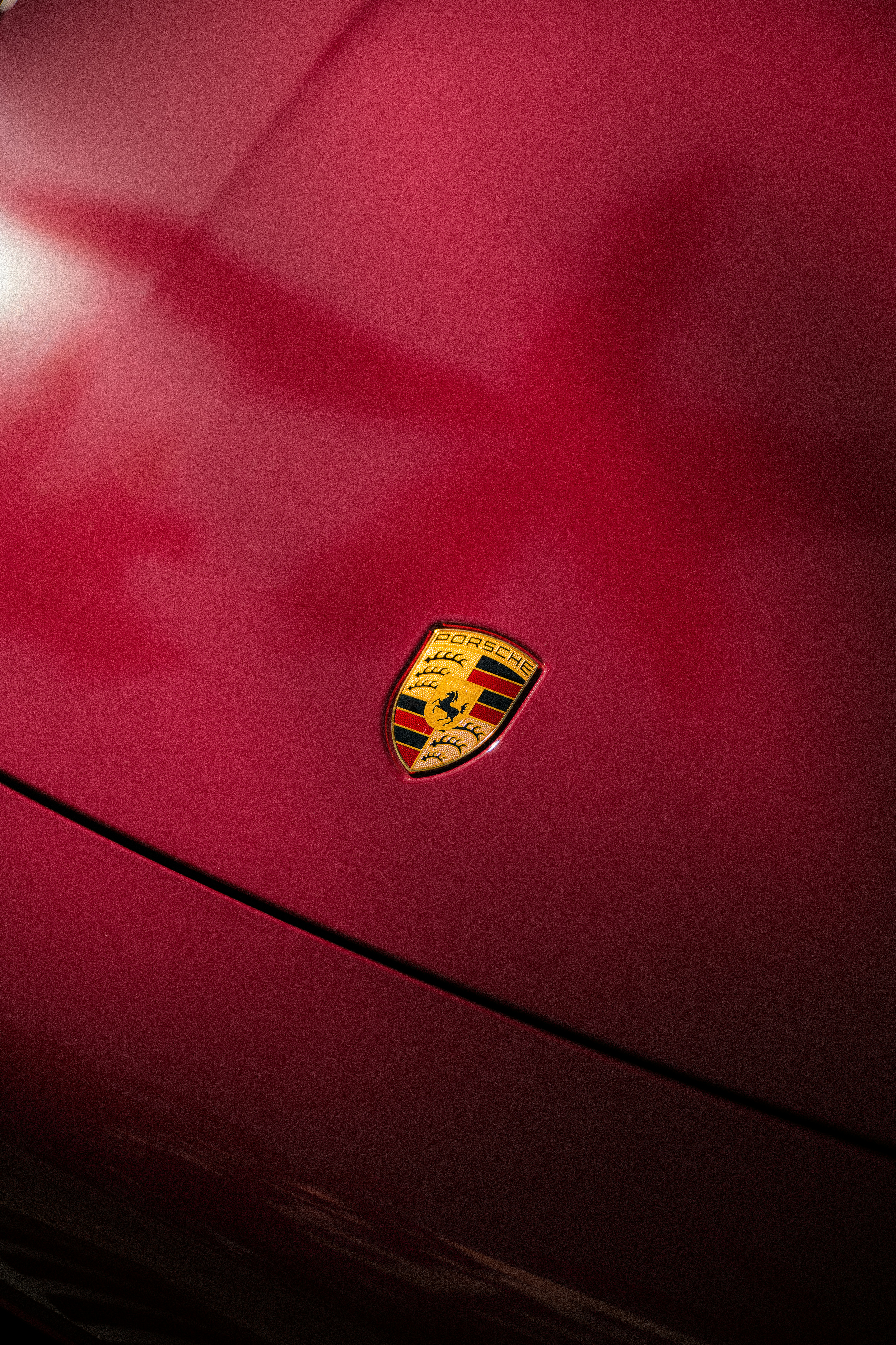 Logo Porsche sul cofano dell'auto rosso.