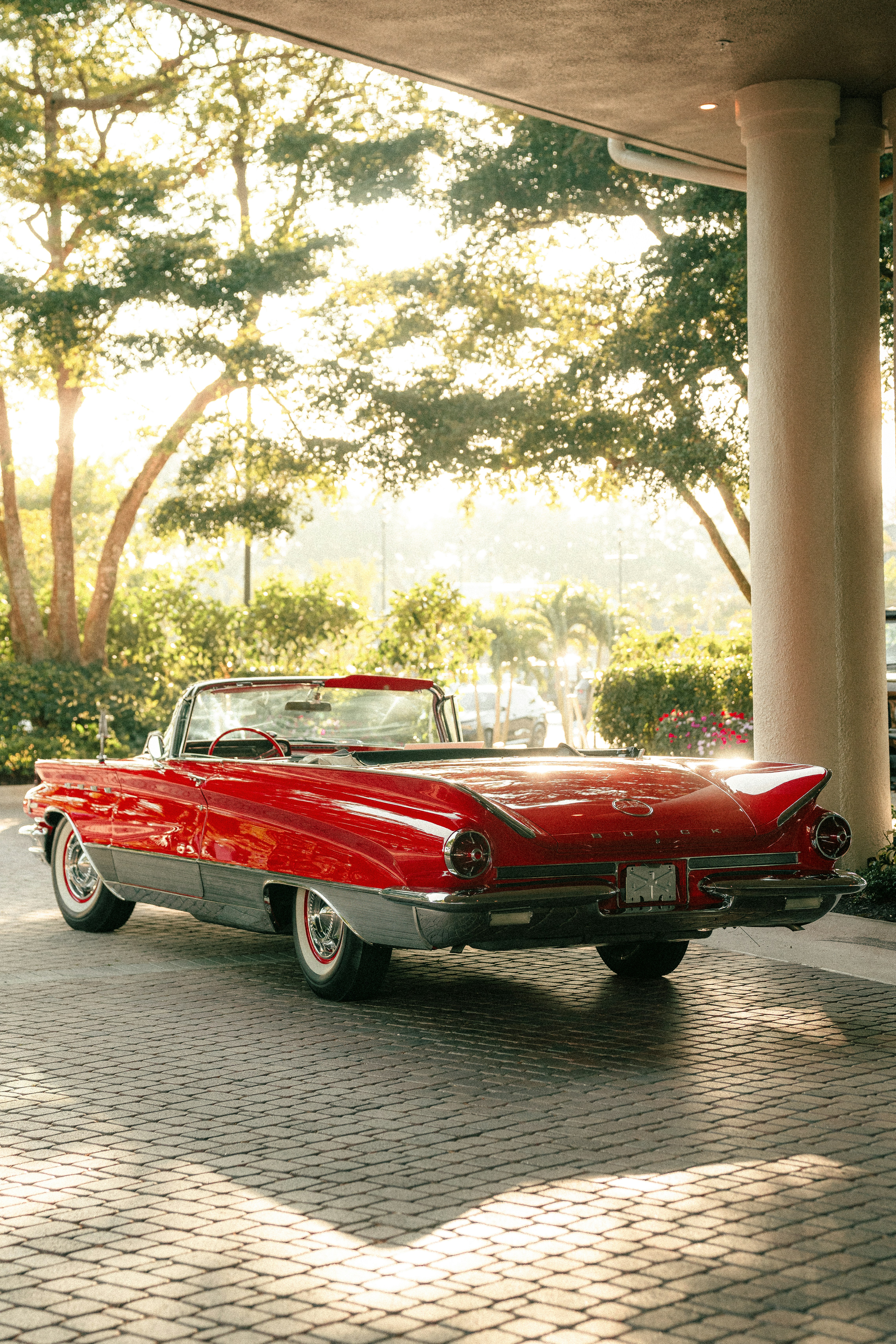 Una decappottabile rossa è parcheggiata sotto un ingresso.