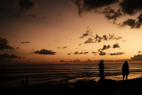 Distant silhouettes along Seminyak Beach at sunset