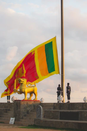 Sri lankan flag with statue and guards at sunrise.