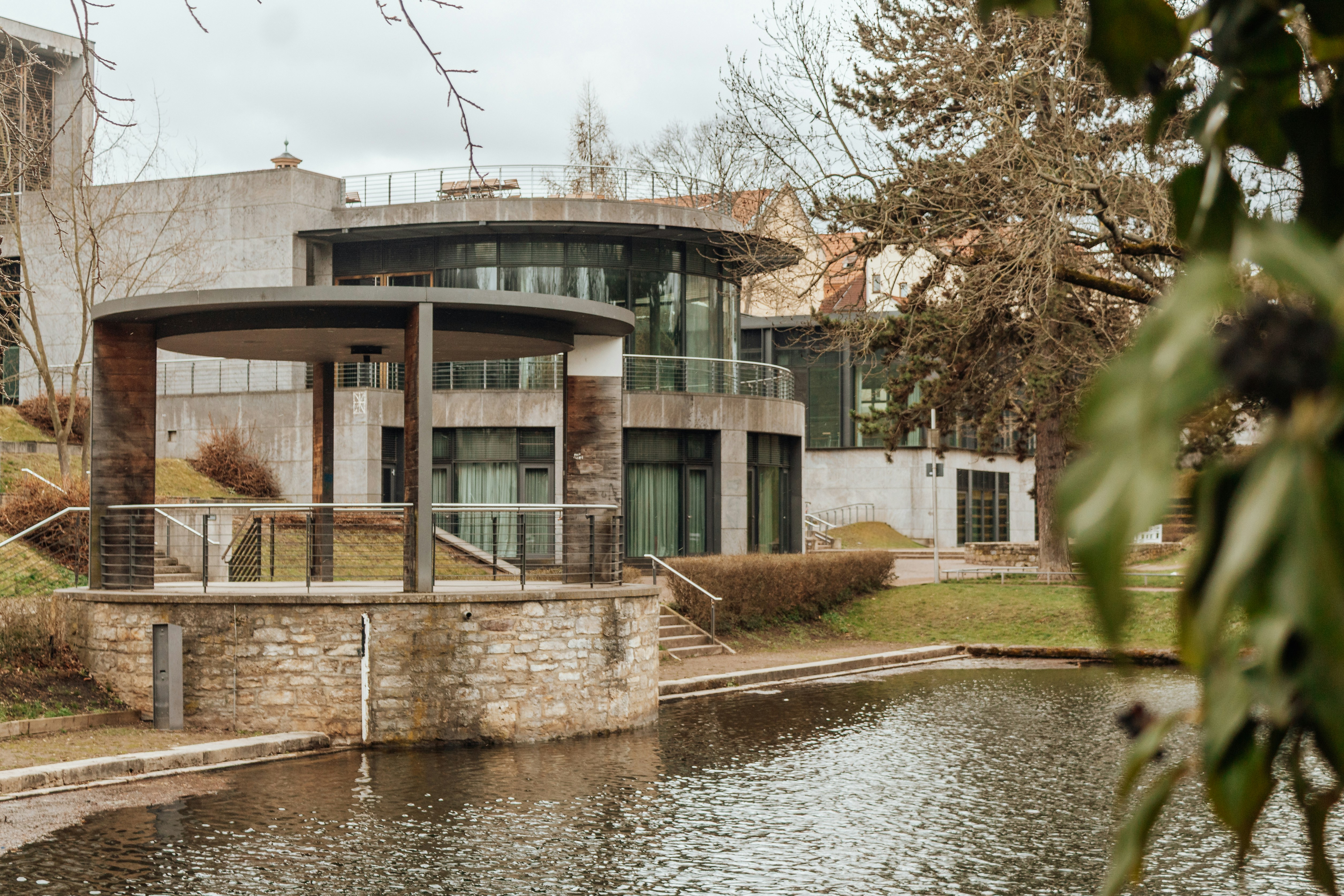 Modern building with a pond and trees.
