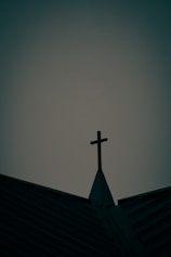 A church roof and cross against a somber sky.