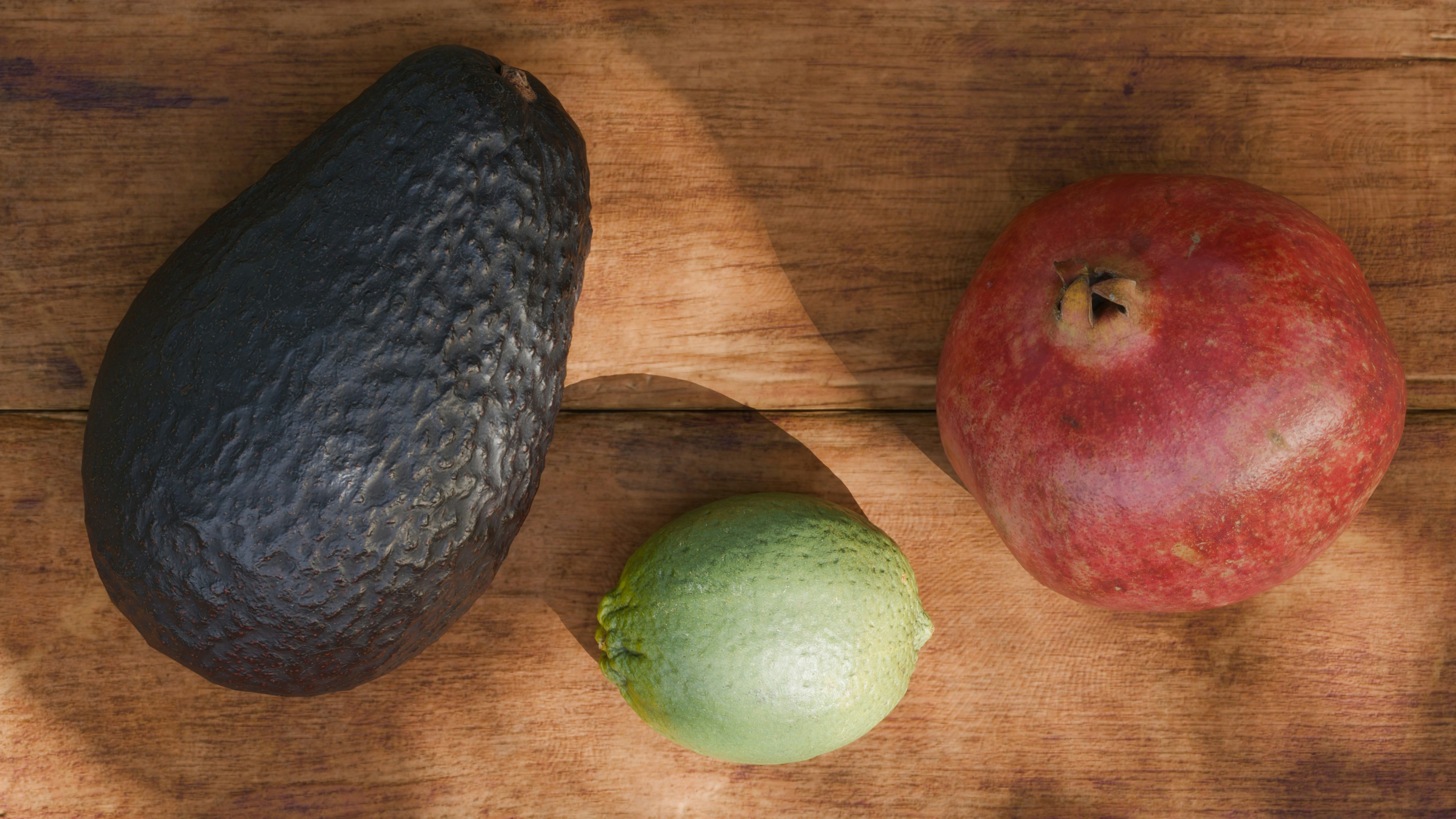 An avocado, lime, and mango lie on wood.