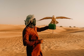 Man holding falcon in the desert.