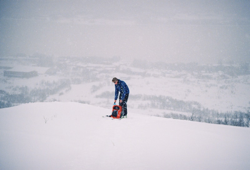 A person stands with a pack in a snowy field.