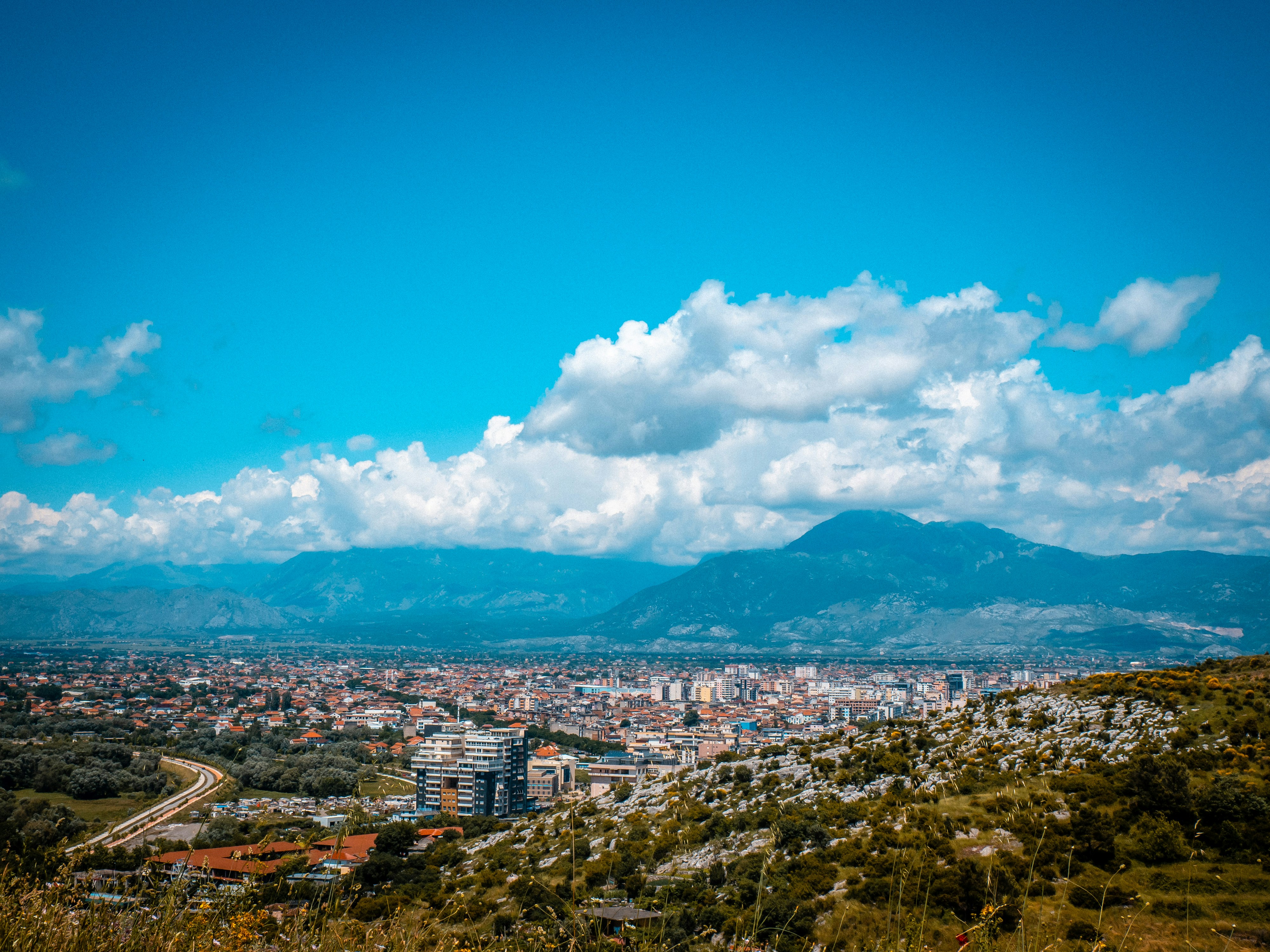 A cityscape view with mountains and blue sky.