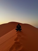 Man meditates on top of a desert dune.