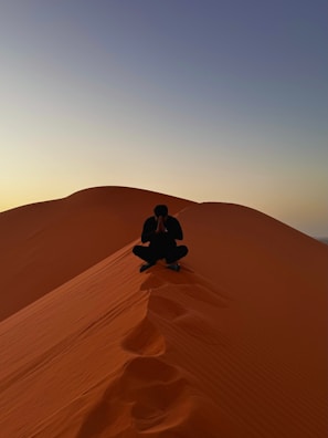 Man meditates on top of a desert dune.