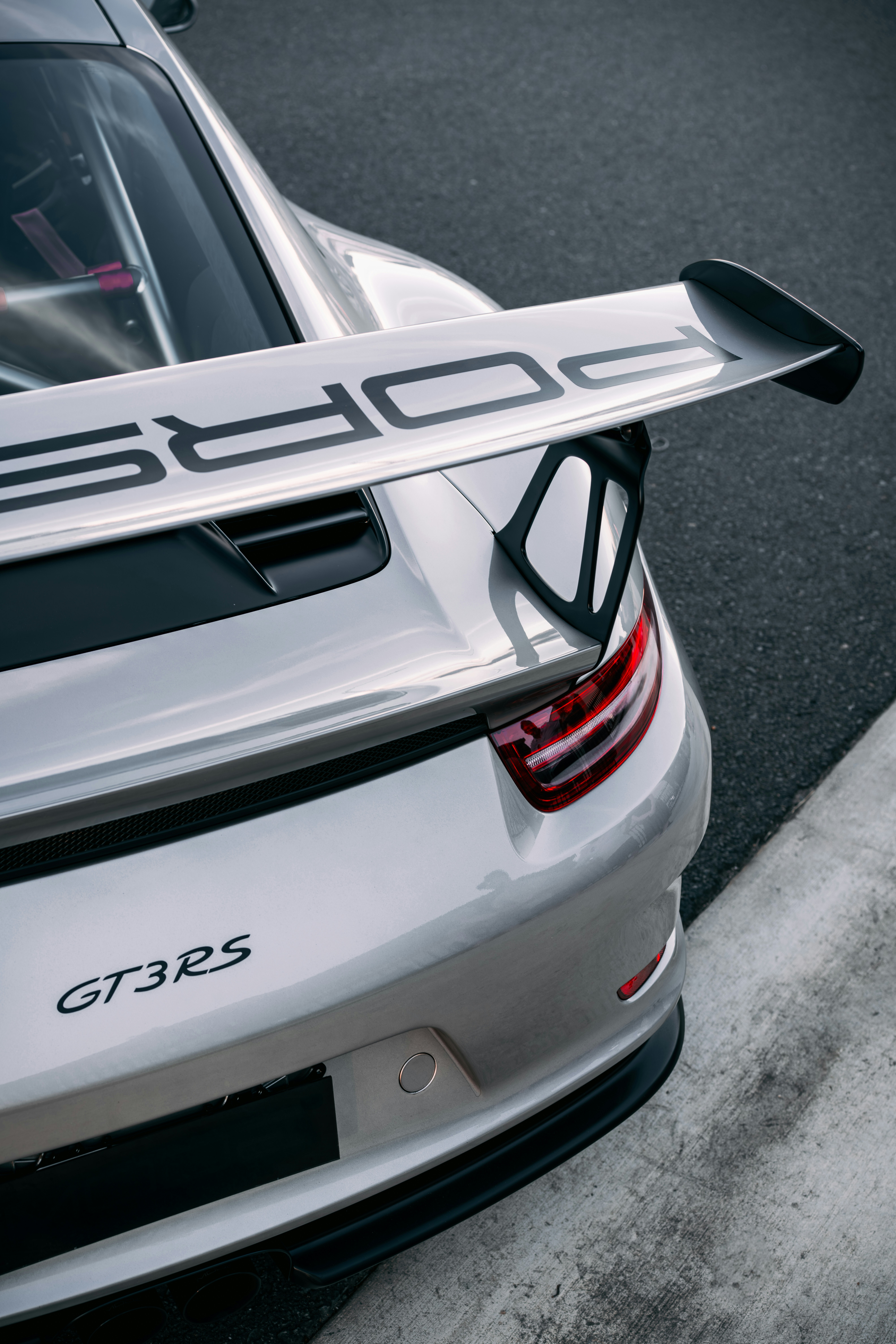 A silver porsche gt3 rs sits on a racetrack.