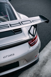 A silver porsche gt3 rs sits on a racetrack.