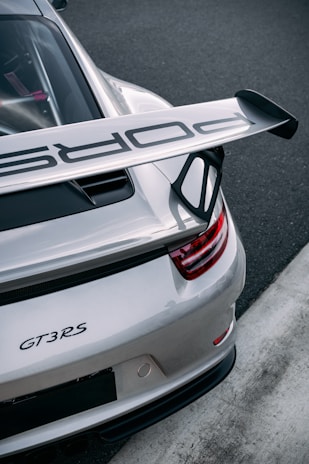 A silver porsche gt3 rs sits on a racetrack.