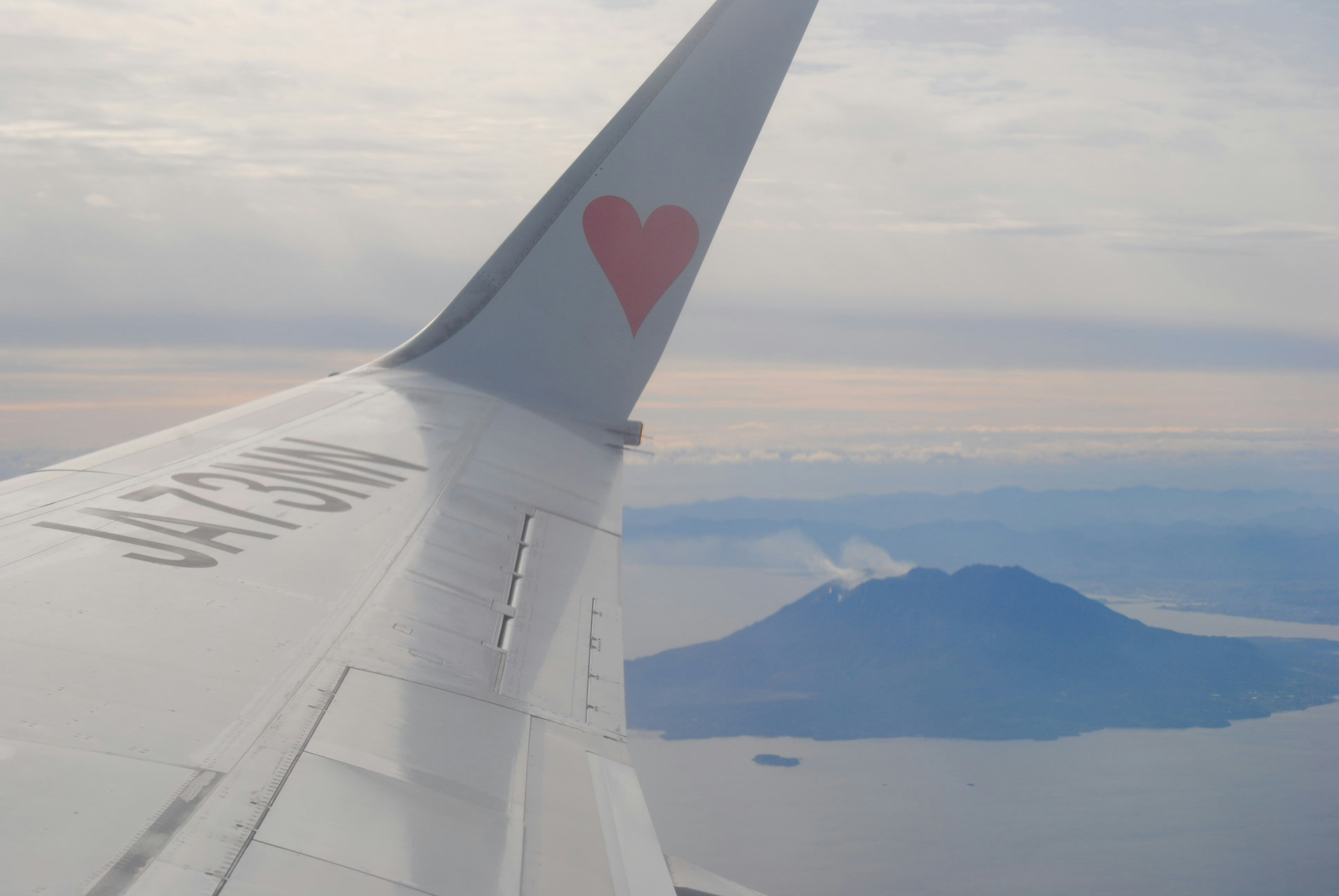 Vue de l’aile d’un avion d’une montagne et d’une mer.