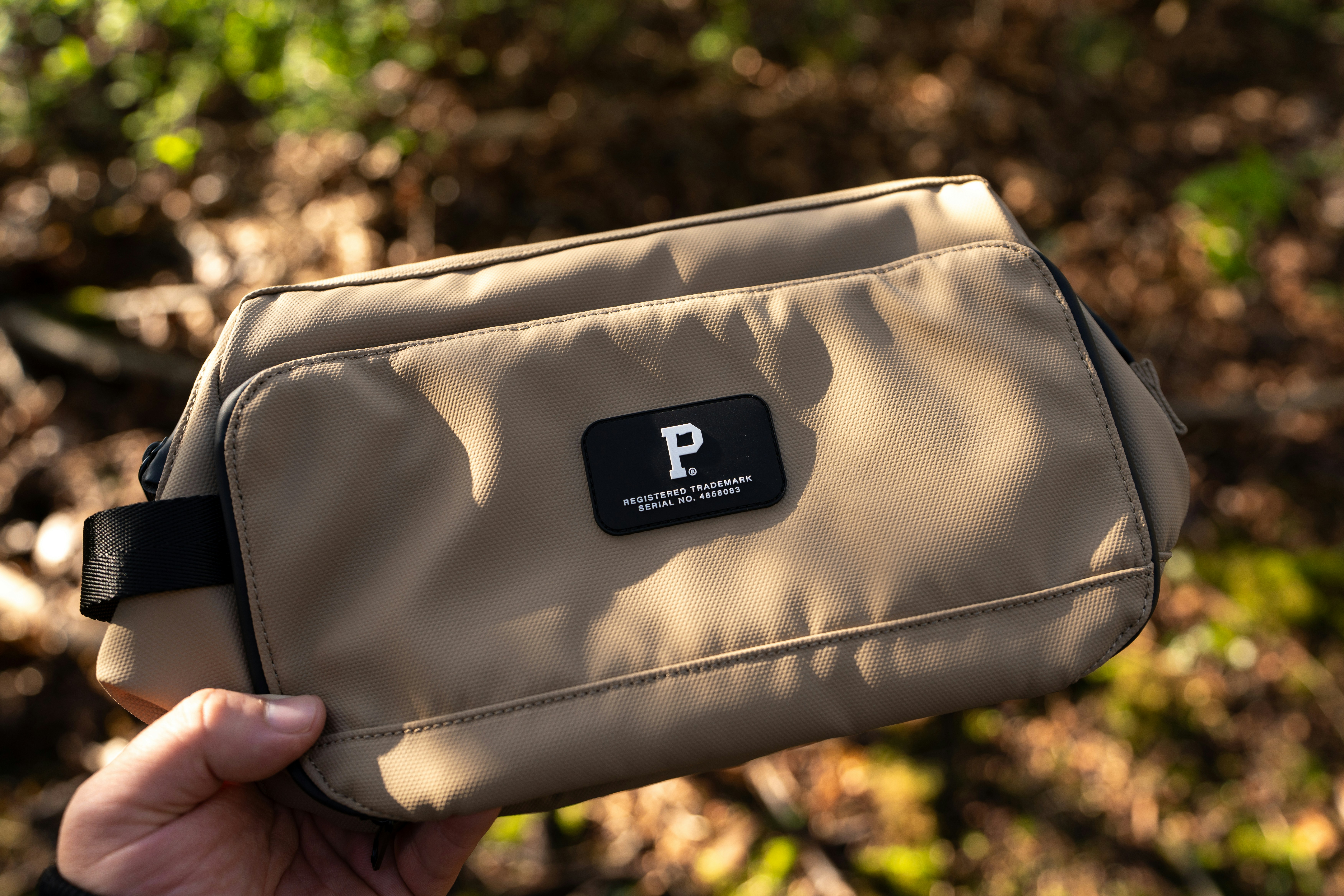 A tan pouch sits on a forest floor.