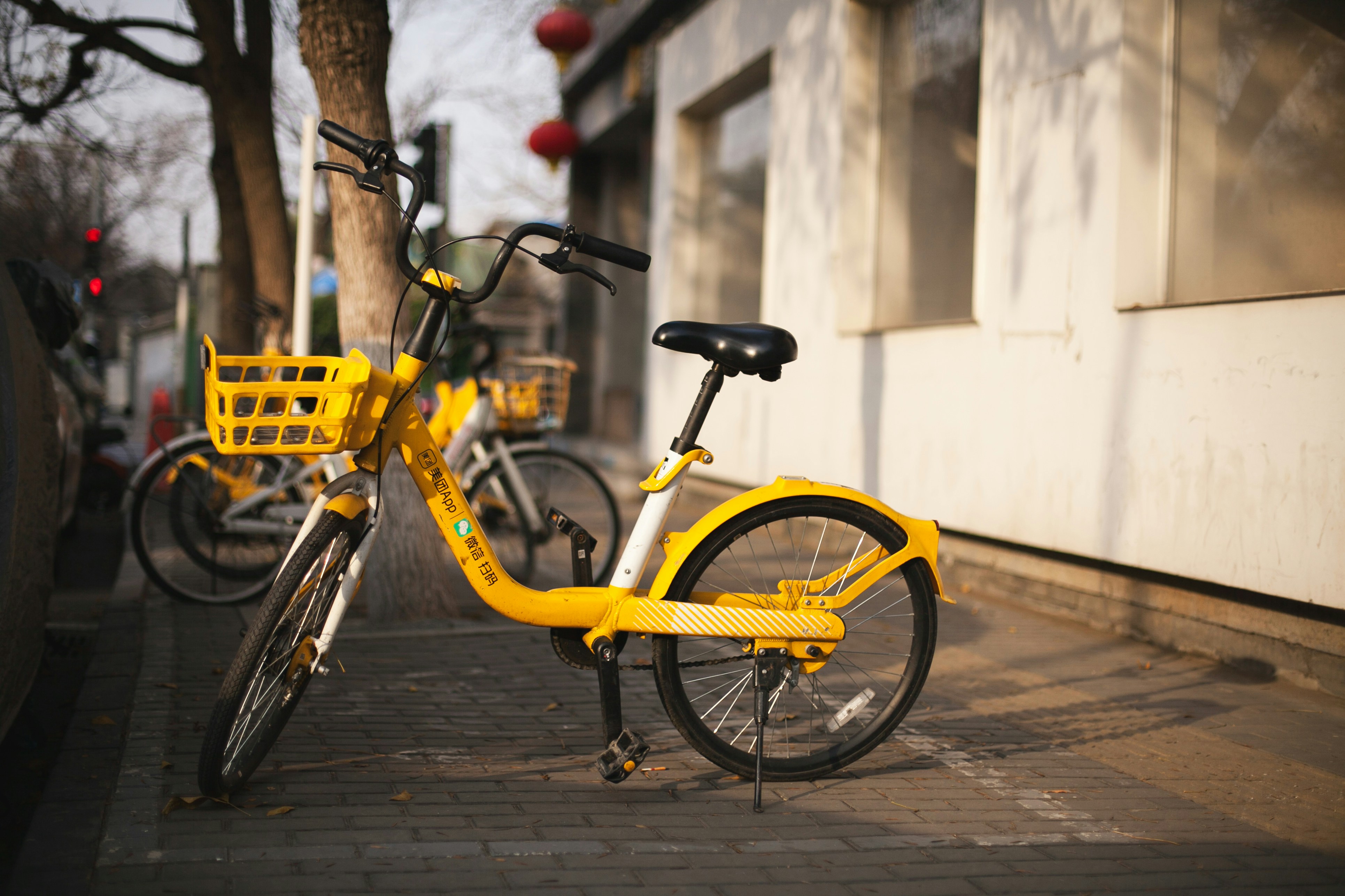 Yellow rental bicycle parked on a city sidewalk.