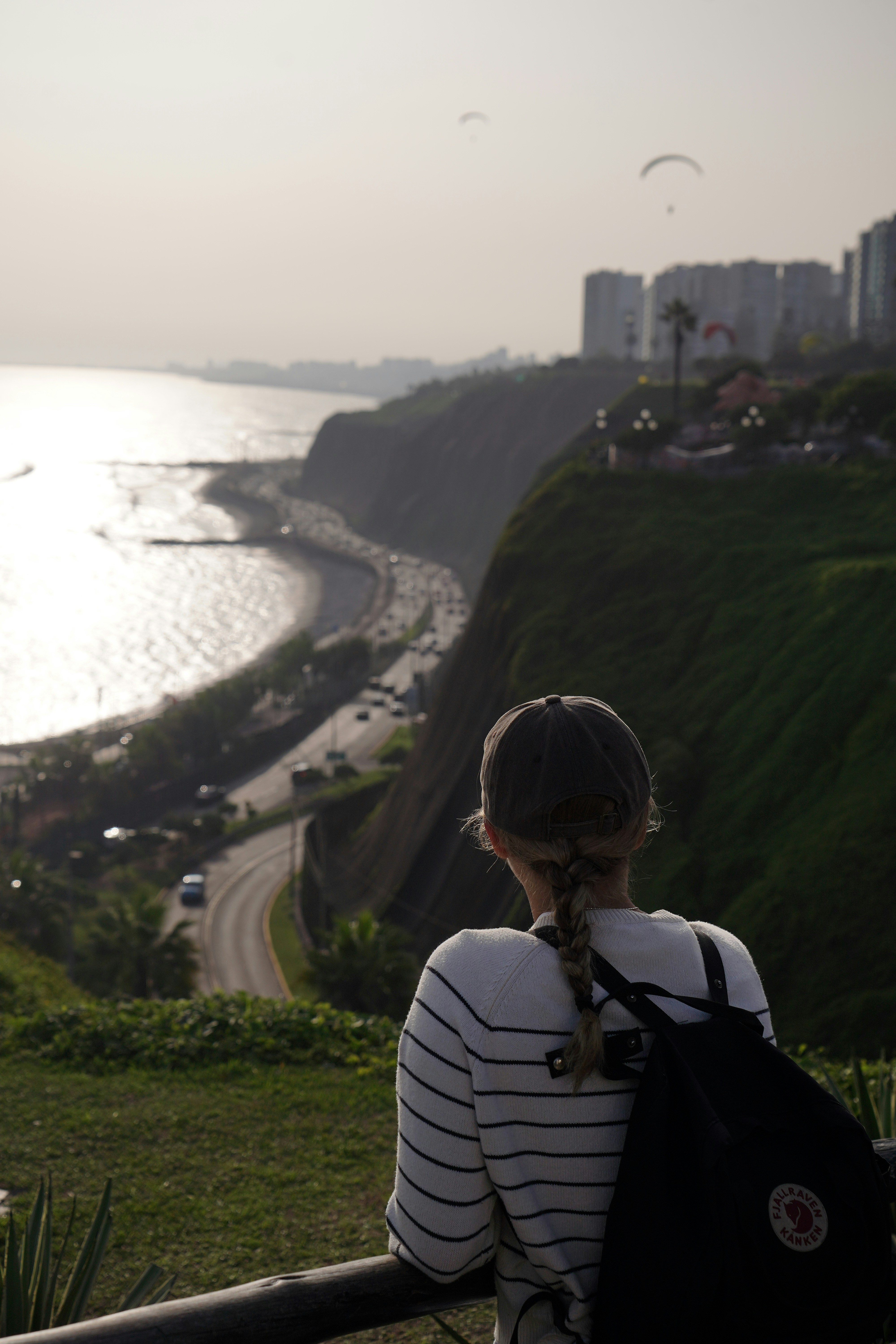Person views coastal city with paragliders.