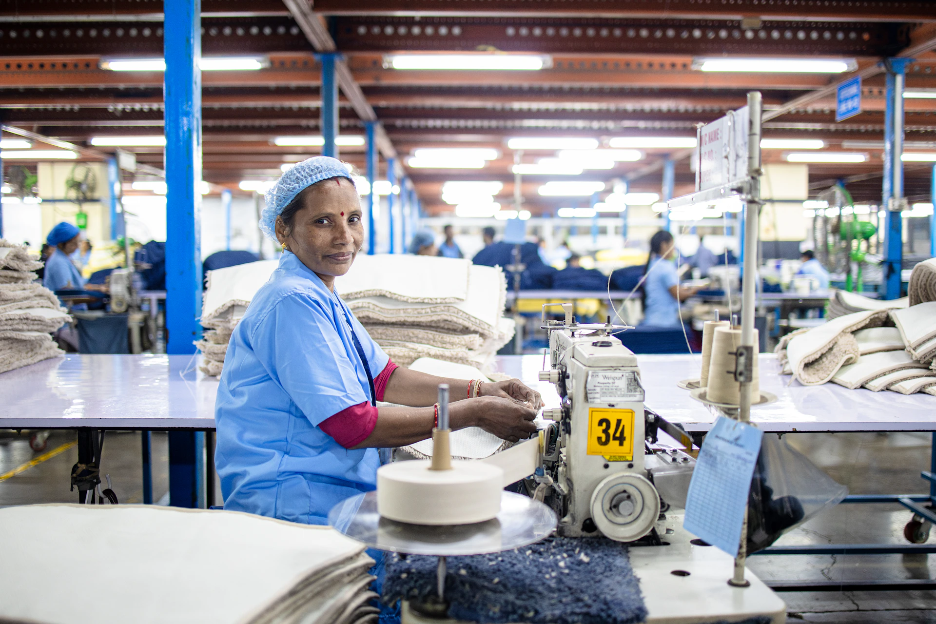 Woman working at a sewing machine in a factory.