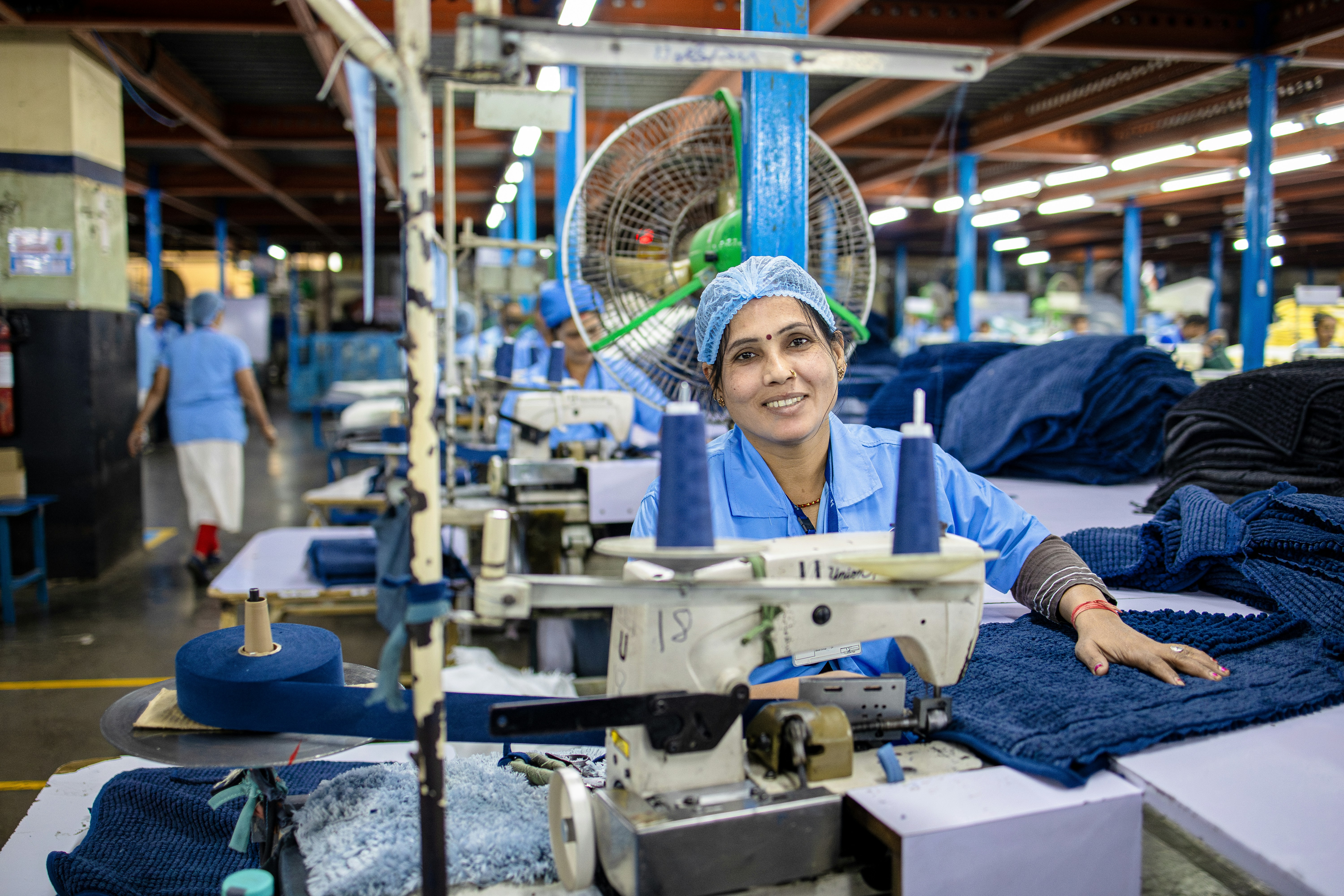 A woman sews denim clothes in a factory.