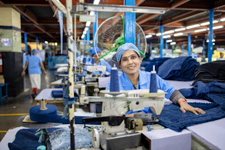 A woman sews denim clothes in a factory.