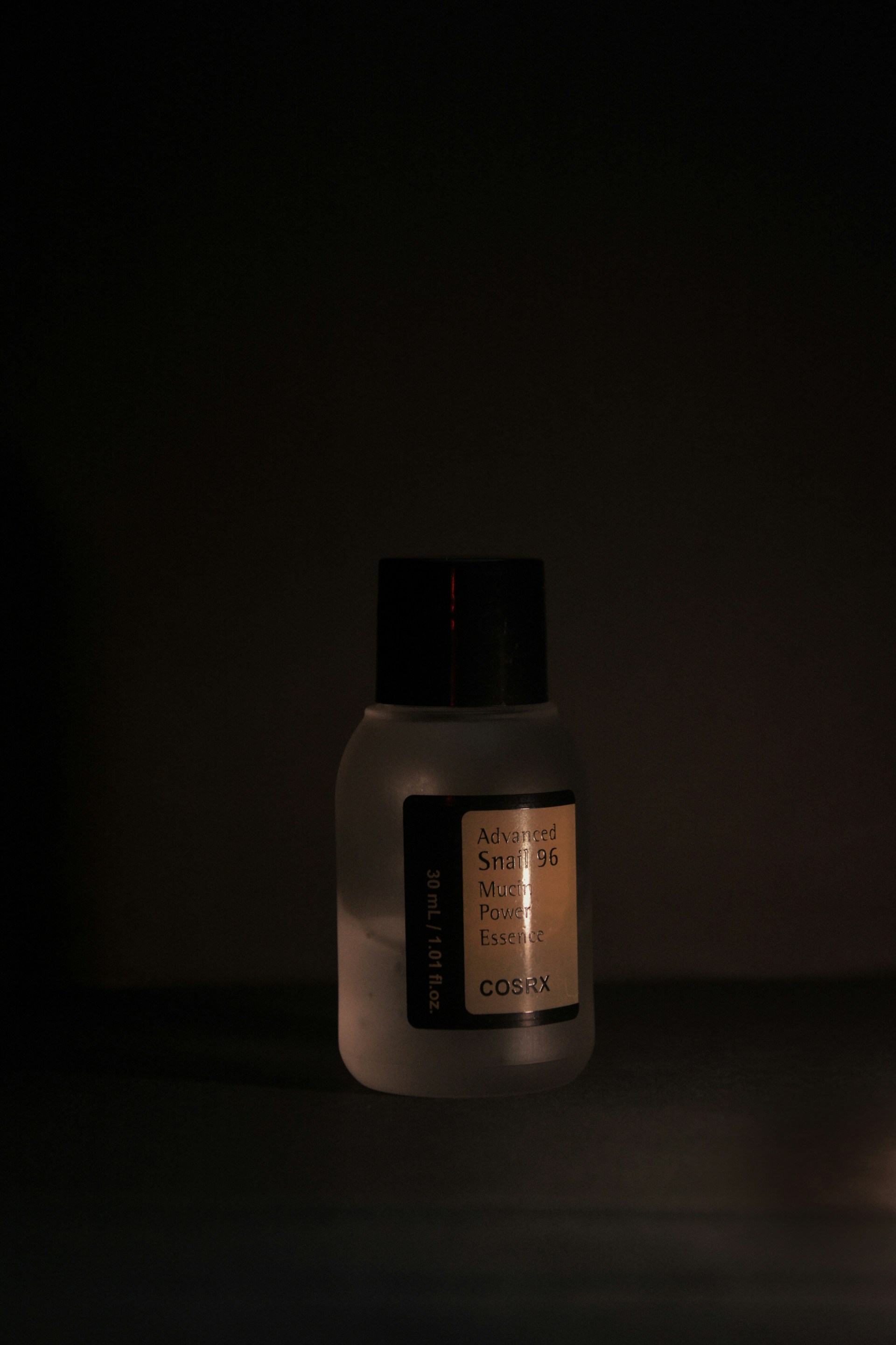 Skincare product bottle in a dimly lit setting.