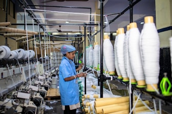 Woman working with industrial textile machines.