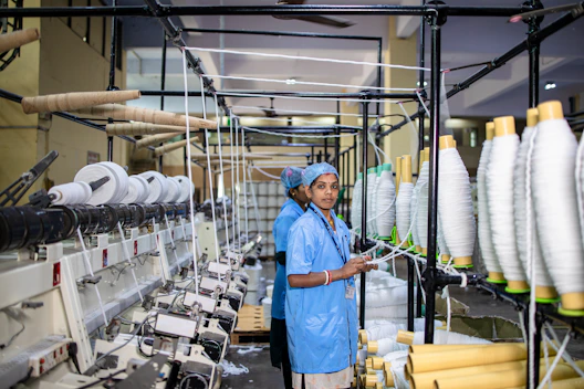 Woman works in a textile factory with spools of thread.