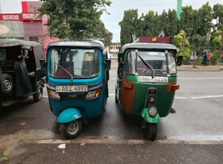 Tuk-tuks are parked side by side on the road.