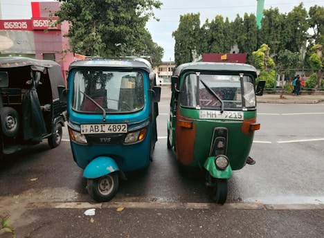 Tuk-tuks are parked side by side on the road.
