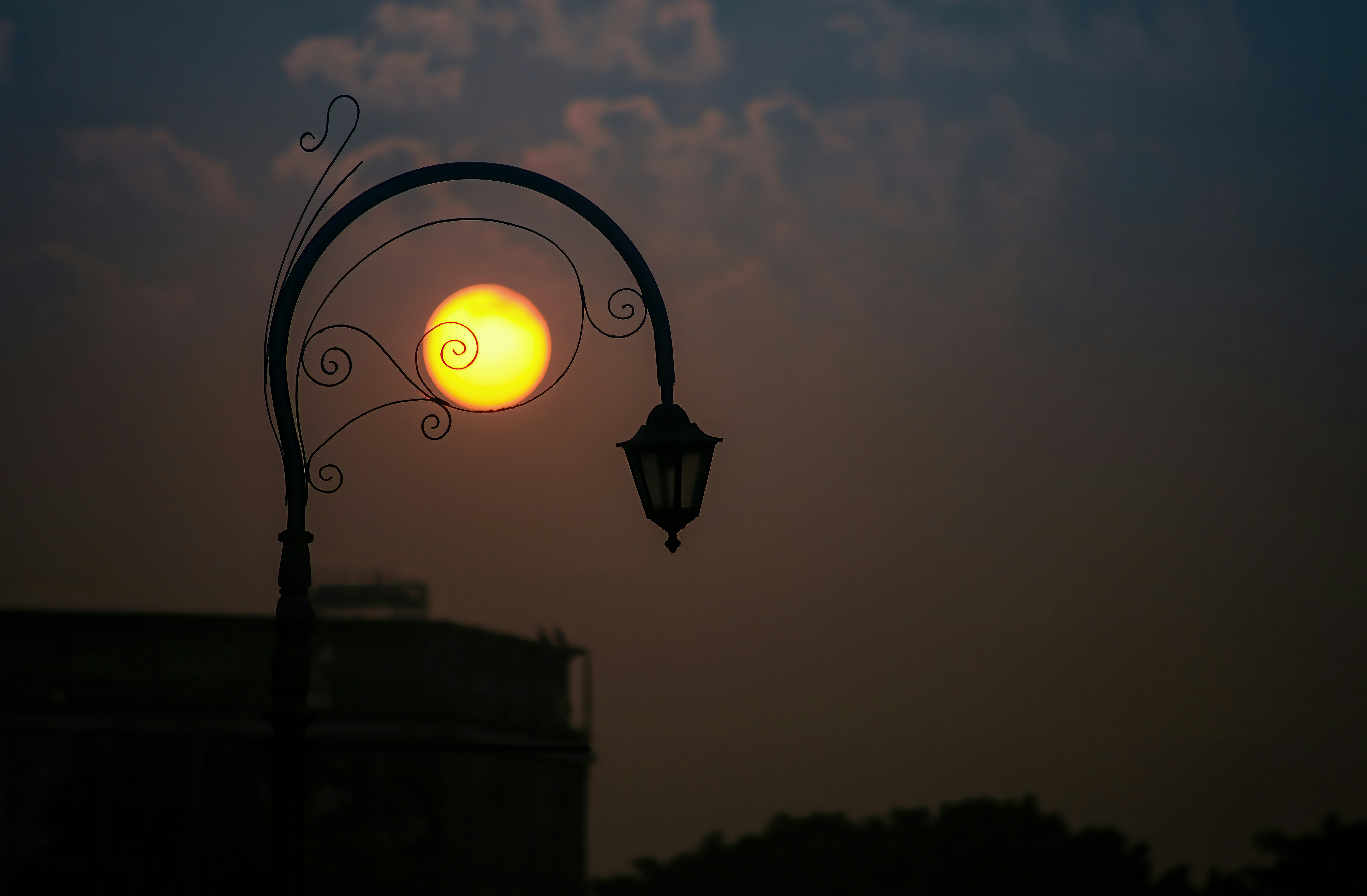 Sun through decorative lamppost at dusk