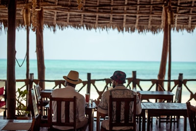Two people relax by the ocean at a cafe.