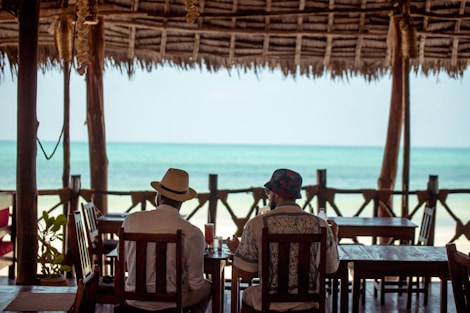 Two people relax by the ocean at a cafe.