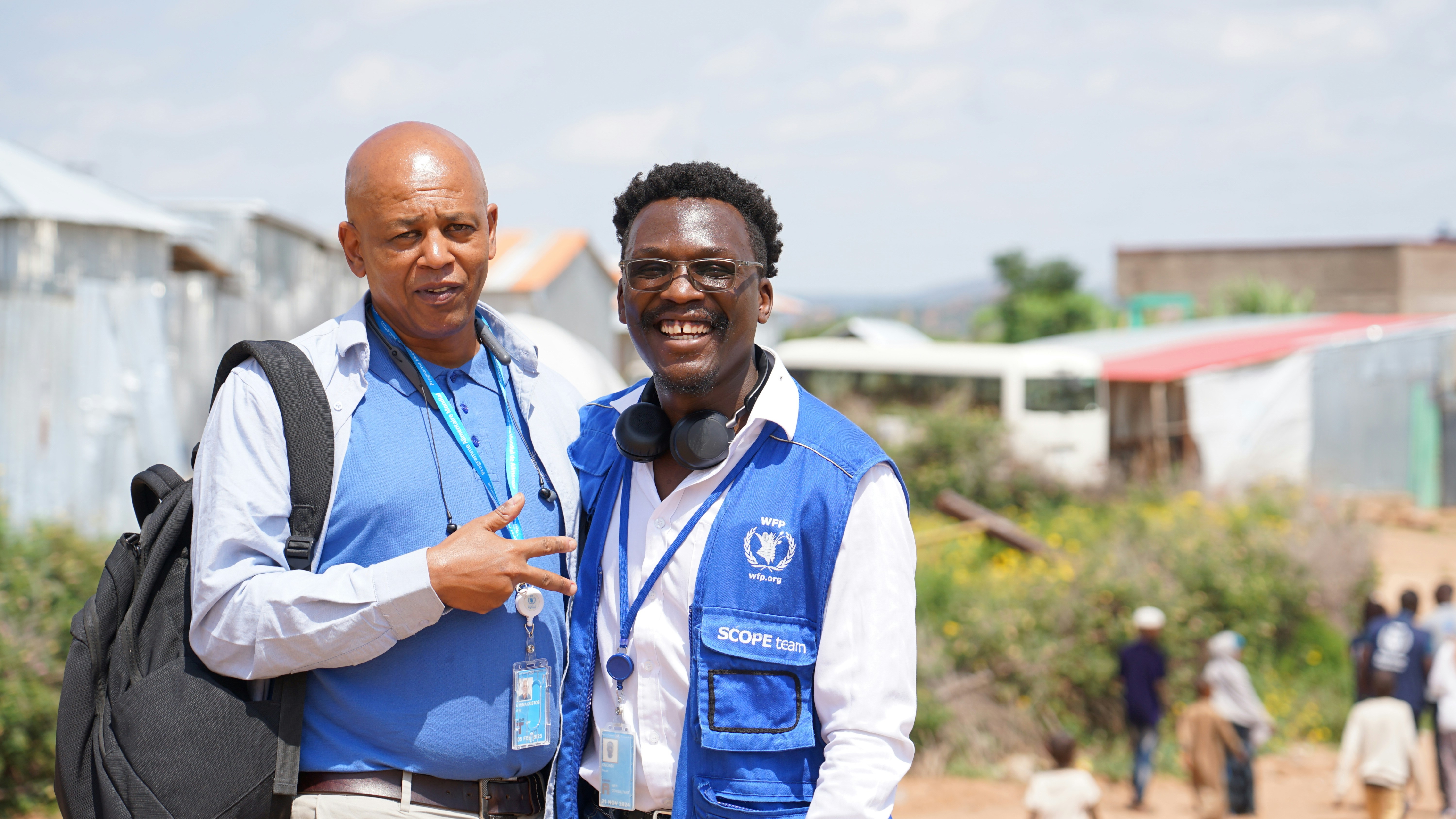 Two men pose together smiling outdoors.
