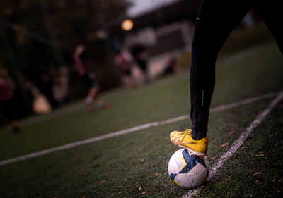 A soccer player stands on the ball.