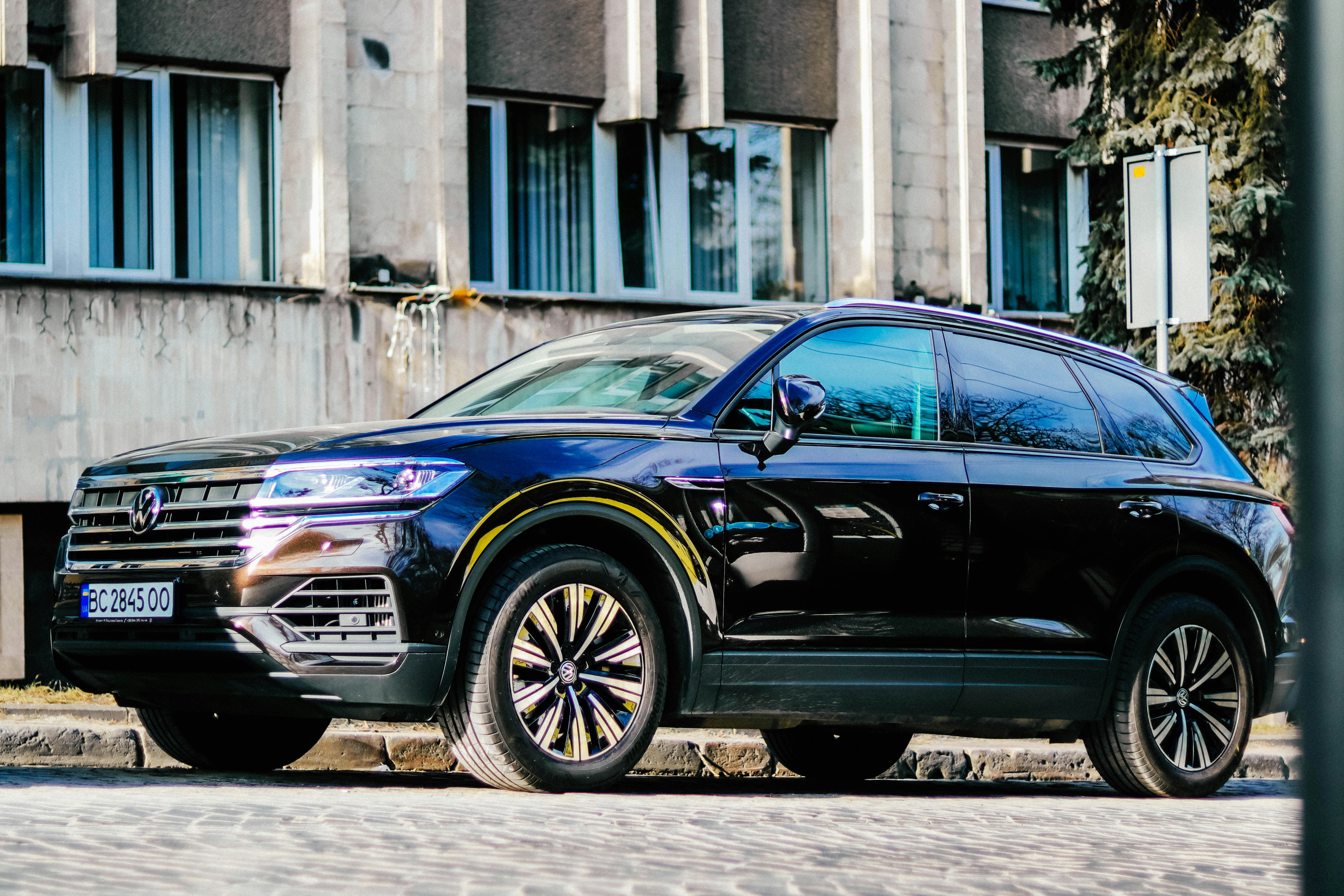 A black suv is parked in front of a building.