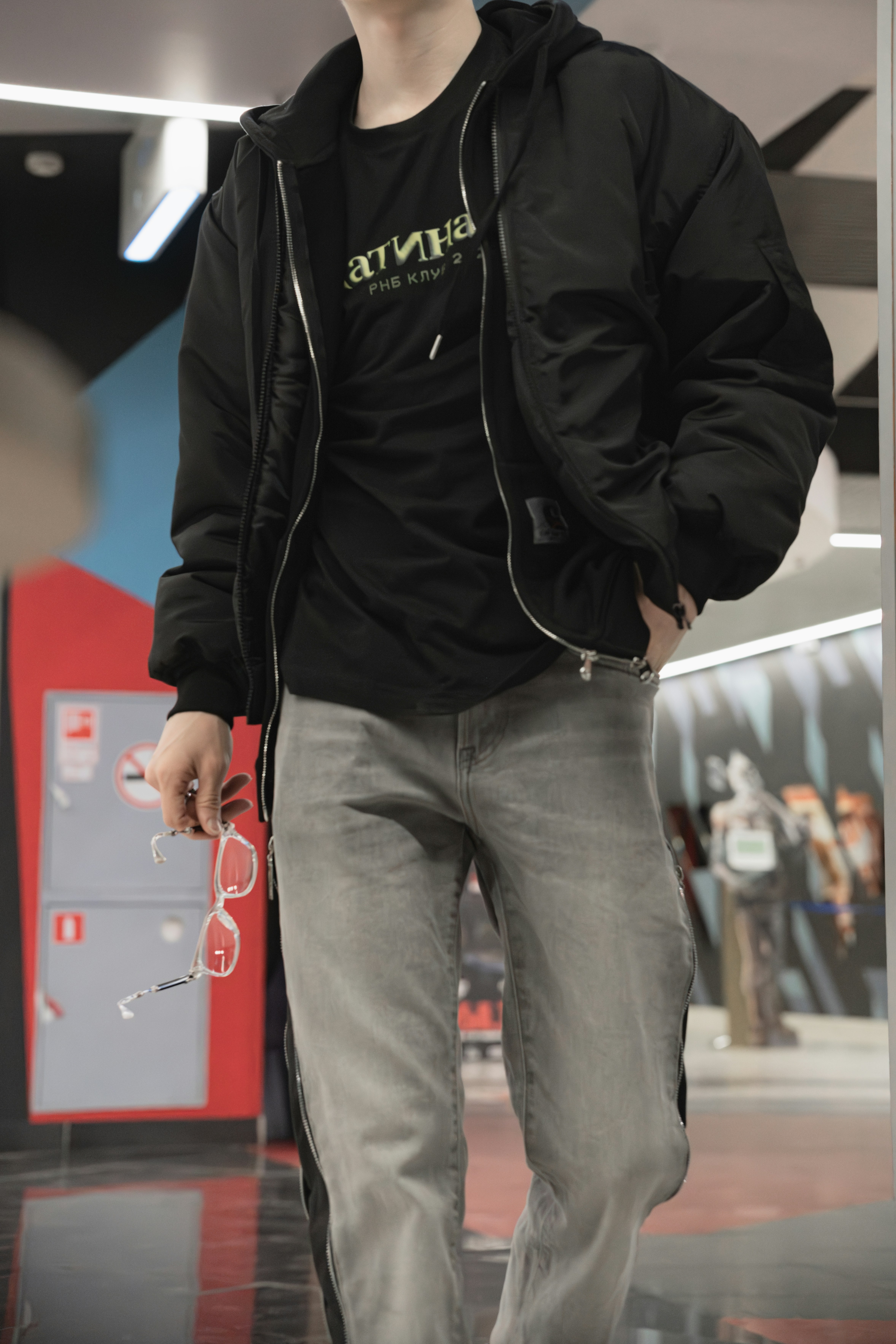 Una persona indossa una giacca nera e jeans.
