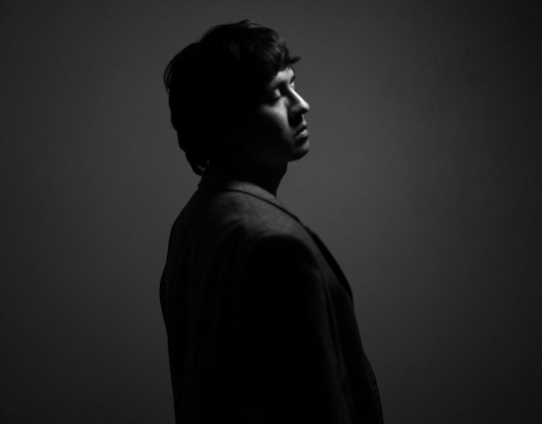 Man in silhouette looks pensively away.,