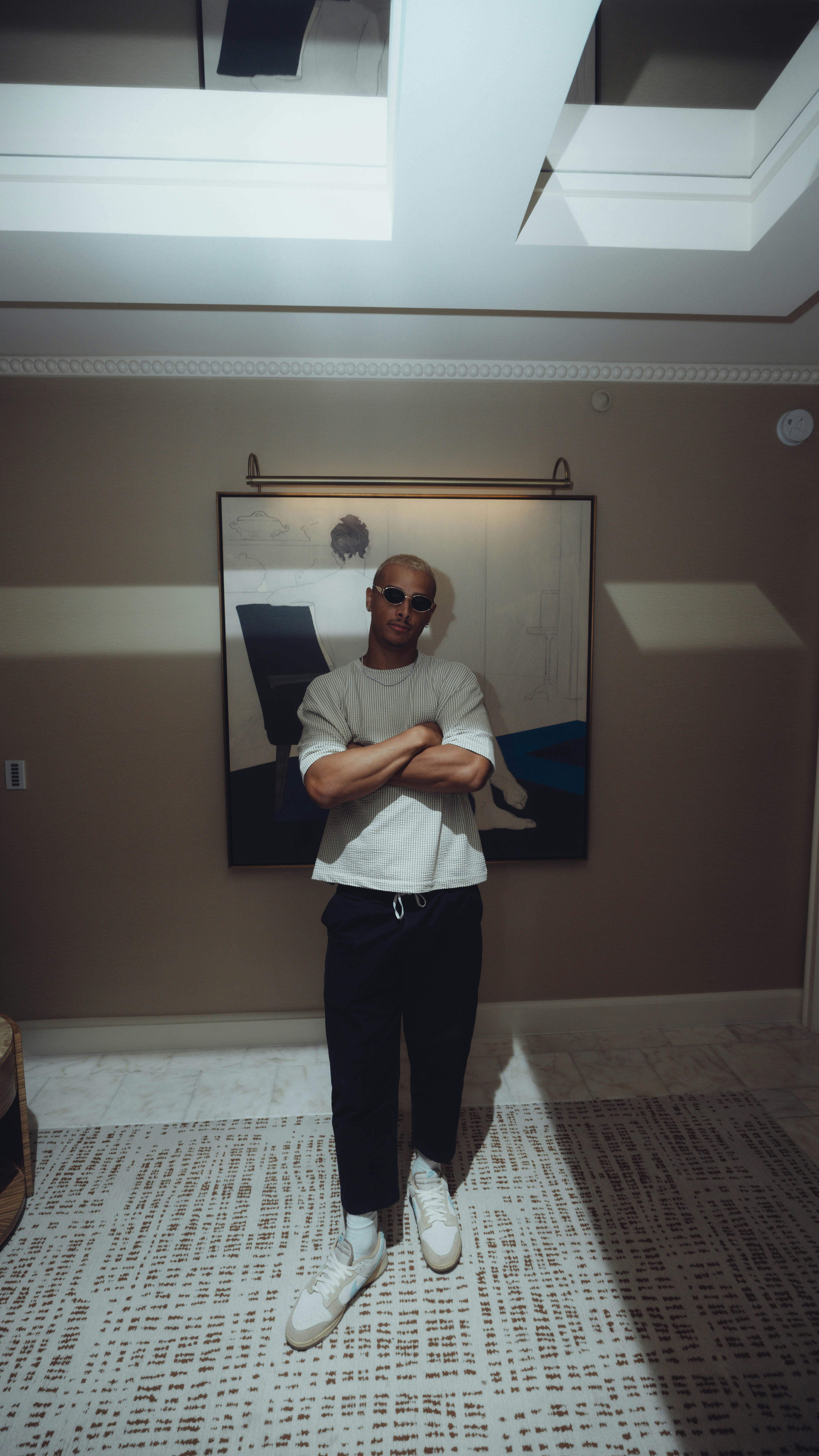 El hombre está de pie confiado en una habitación con los brazos cruzados.