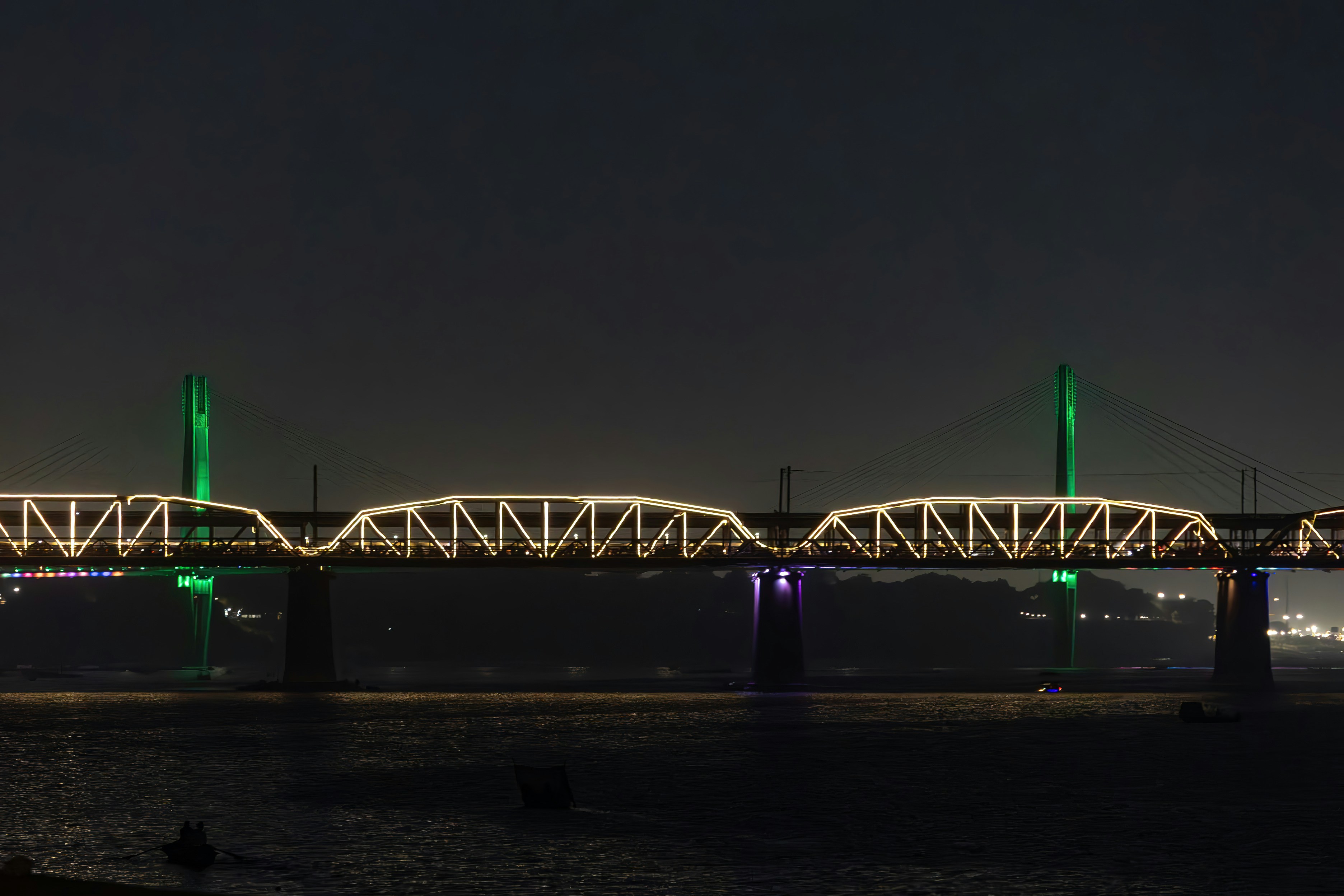 Illuminated bridge at night with green lights.