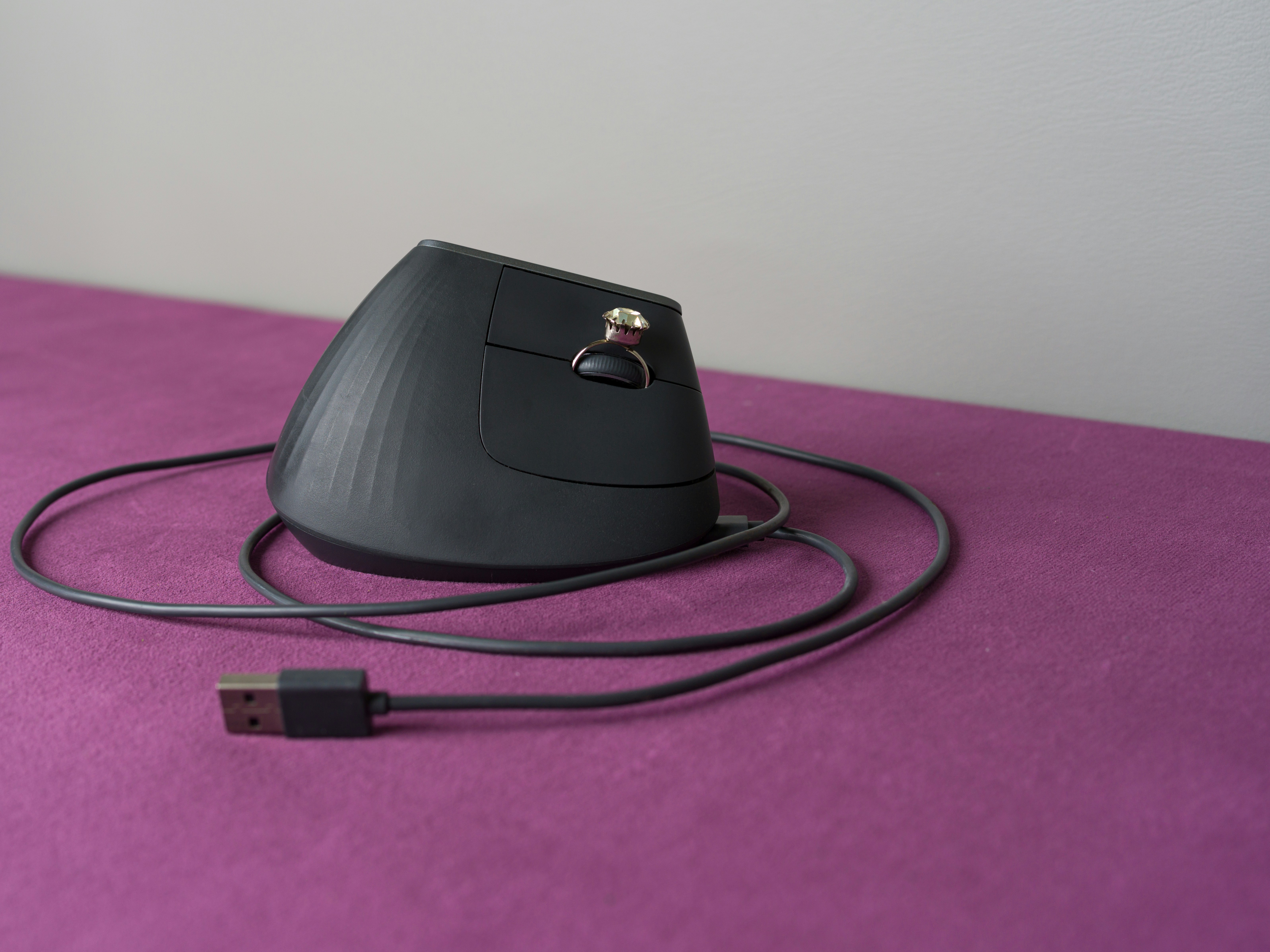 An ergonomic computer mouse rests on a purple surface.
