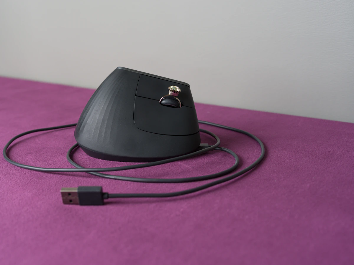 An ergonomic computer mouse rests on a purple surface.