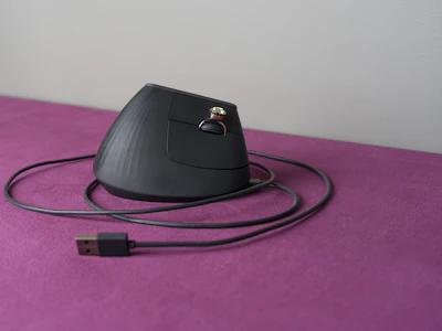 An ergonomic computer mouse rests on a purple surface.