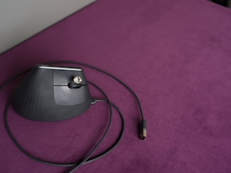 Ergonomic mouse sits on a purple surface.