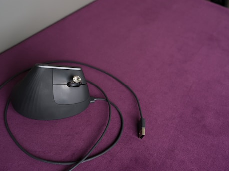 Ergonomic mouse sits on a purple surface.