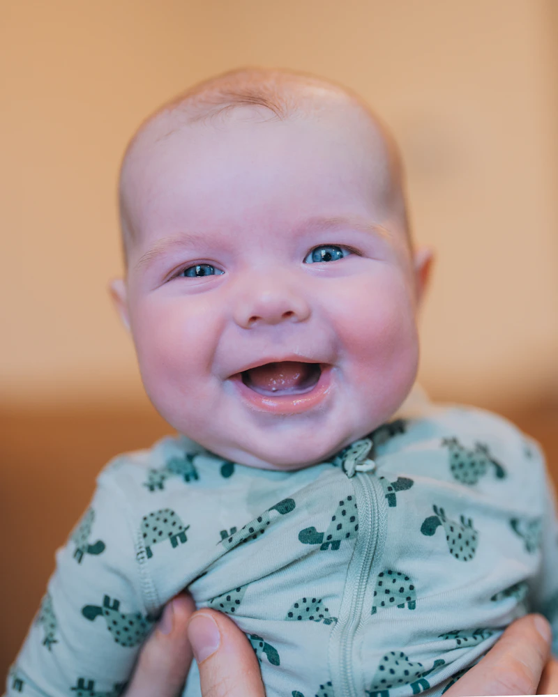 Close-up of a smiling baby being held by a parent