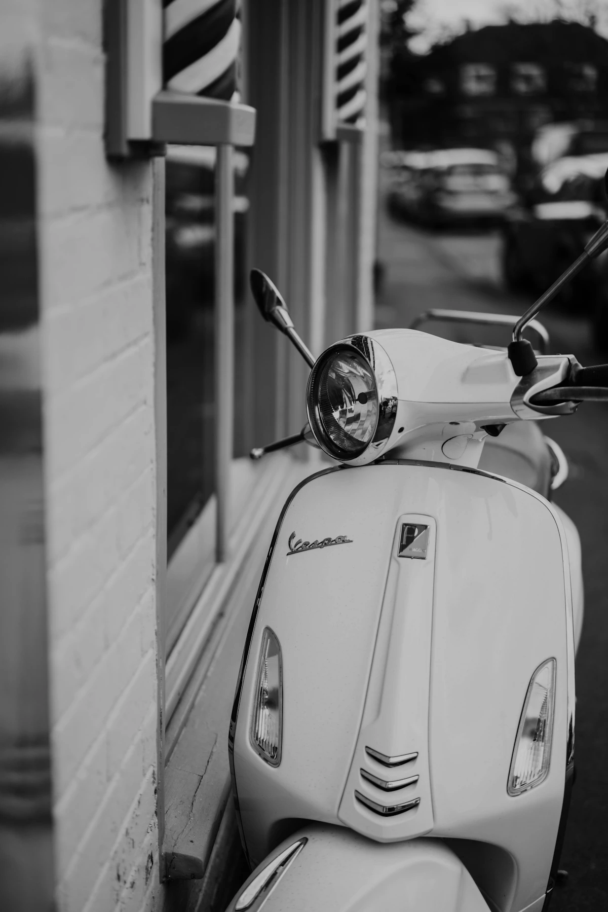 Classic Vespa scooter parked outside a barber shop
