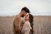 Couple looks at each other lovingly in a field.