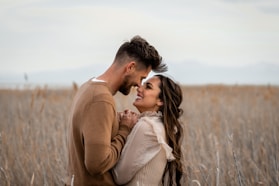 Couple looks at each other lovingly in a field.