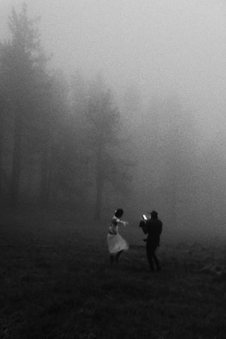 A photographer captures a dancing woman in a misty forest.