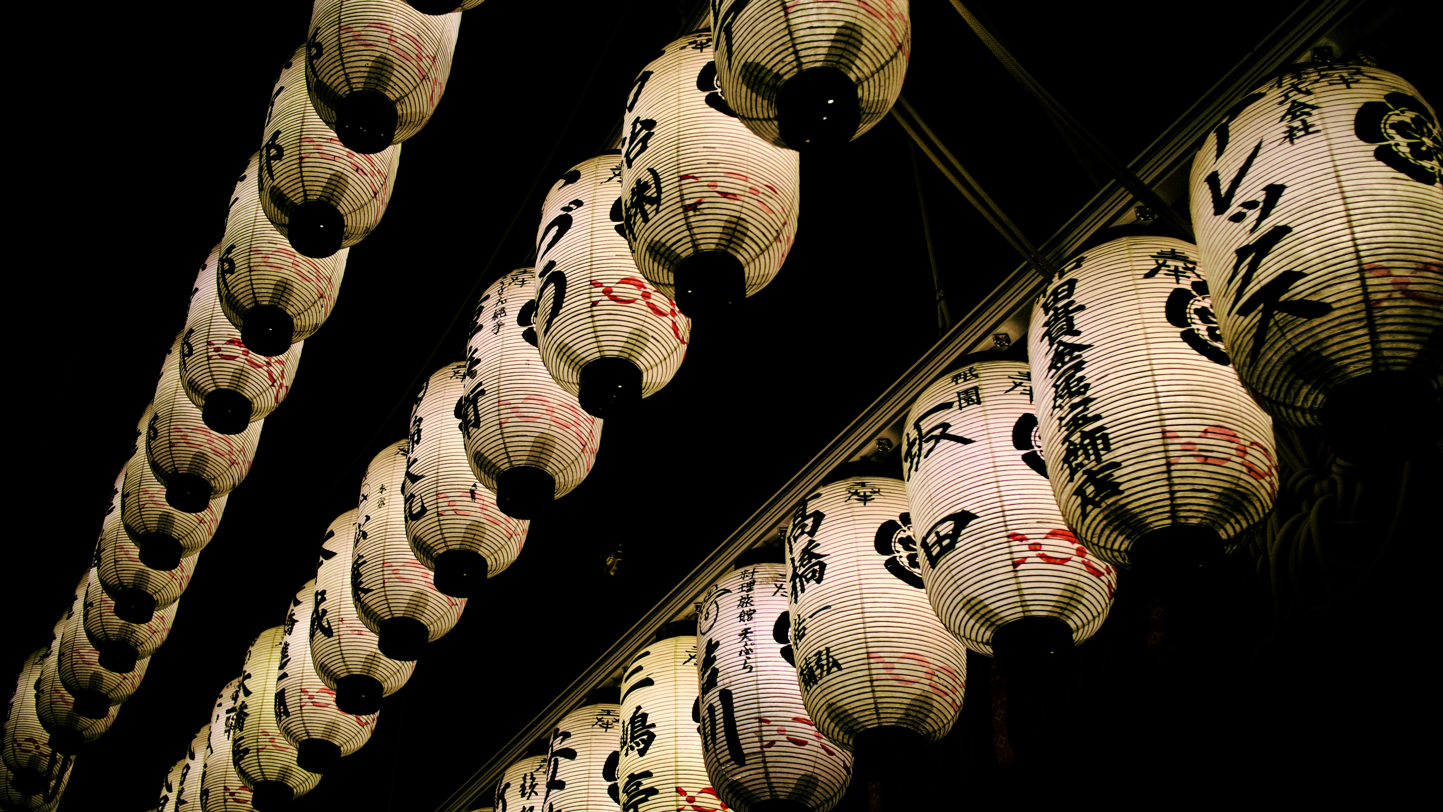 Paper lanterns hang, illuminating the night sky.
