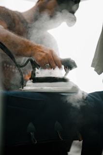 Man irons clothes with a vintage iron.